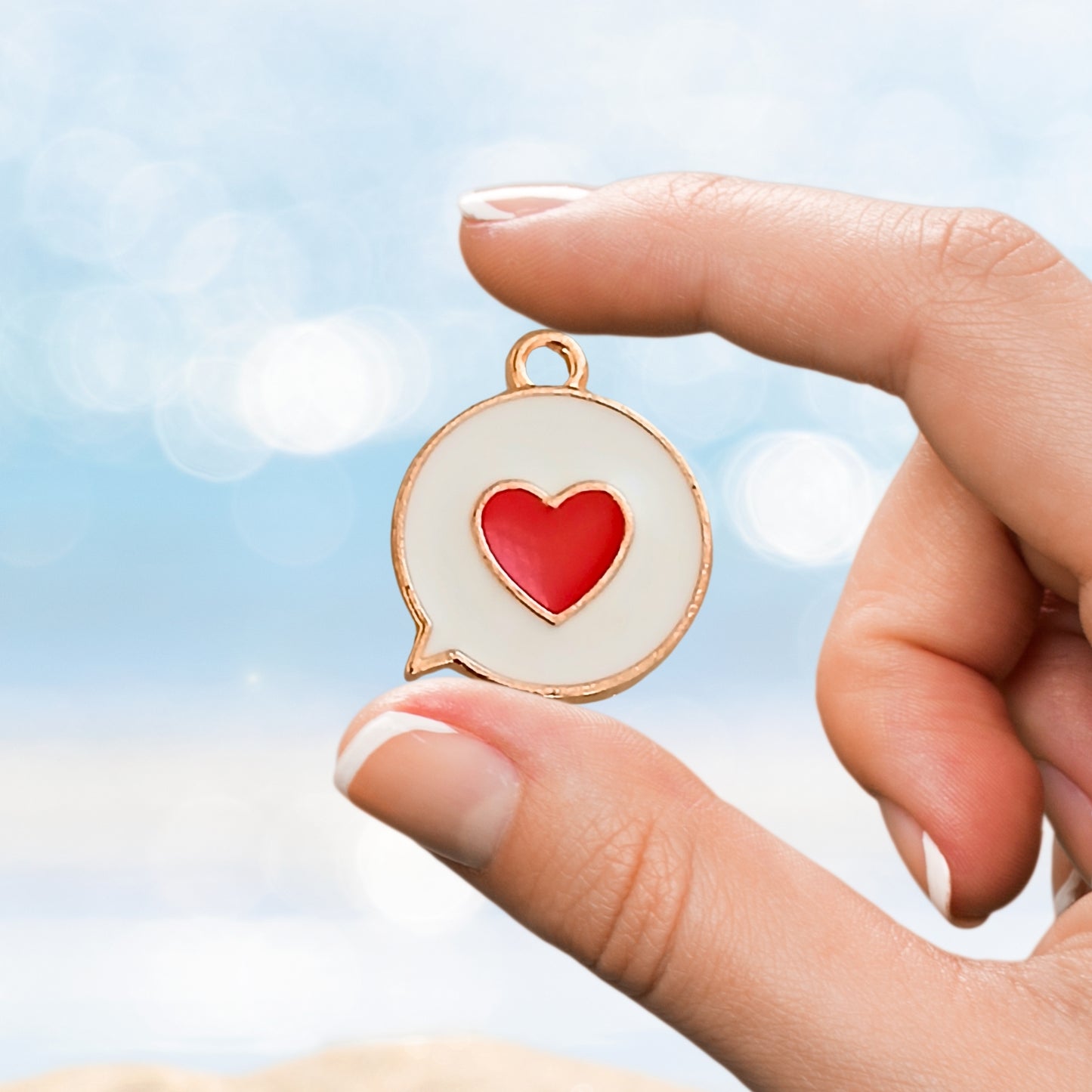 Hand holding small enamel love heart charm