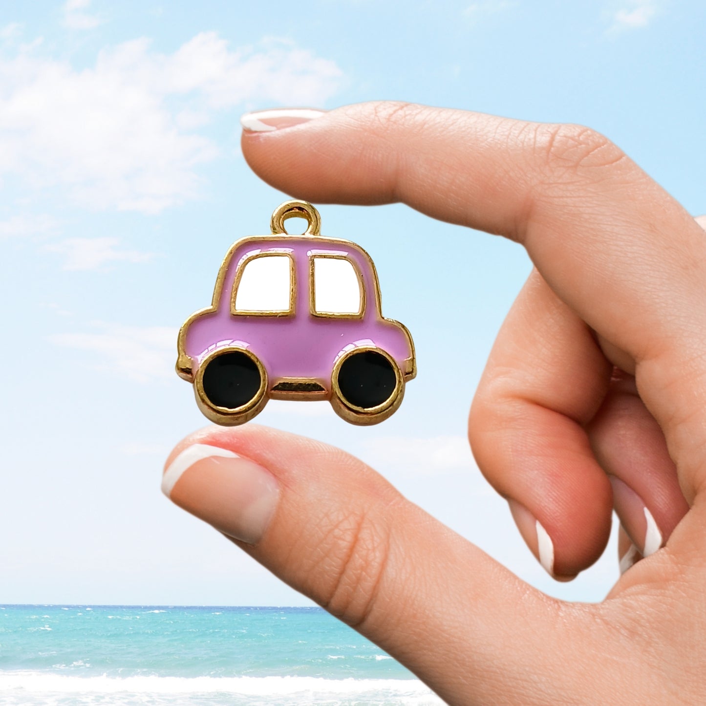 Hand holding a small purple car-shaped enamel charm with gold trim.