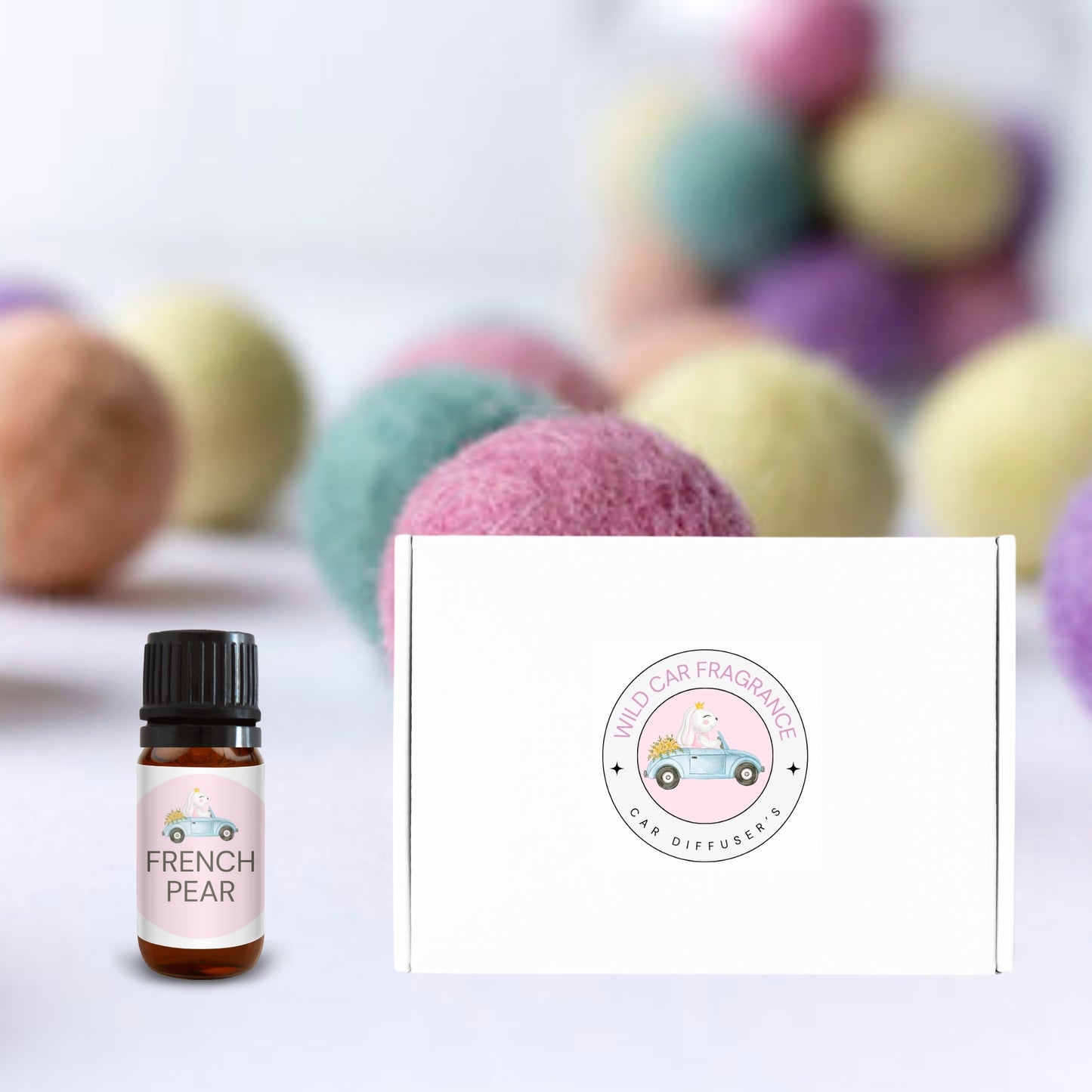 French Pear essential oil bottle beside branded gift box with pastel felt balls in soft focus in the background.