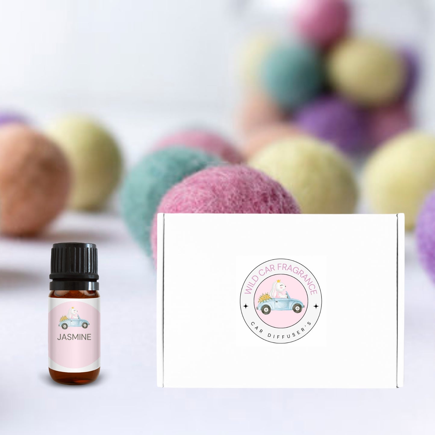Product gift box and jasmine fragrance oil bottle displayed with pastel wool balls blurred in the background