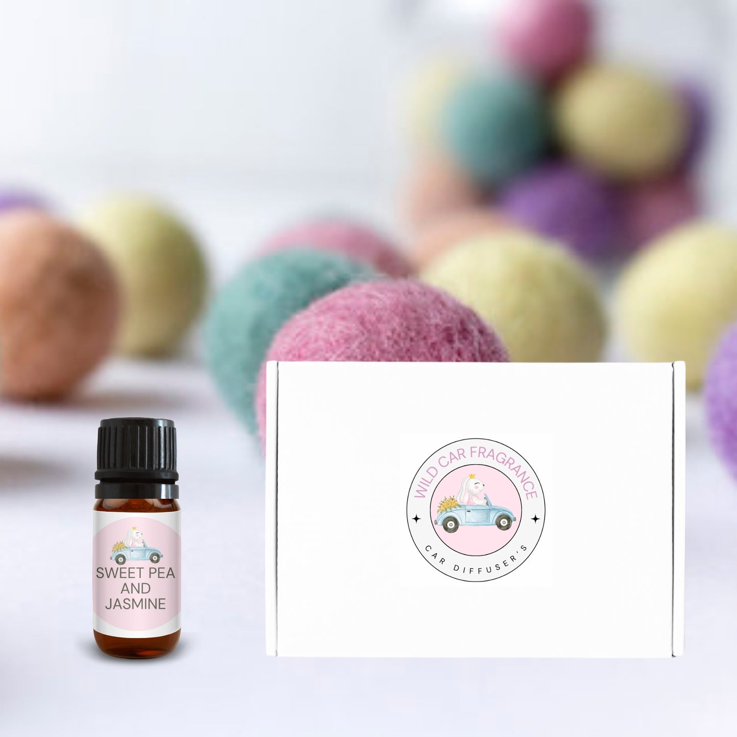 Sweet Pea & Jasmine car diffuser gift box with pink fragrance bottle, displayed among colourful felt balls