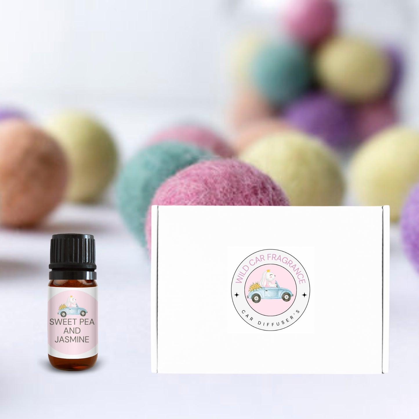 Gift box with Sweet Pea & Jasmine fragrance oil in front of soft-focus pastel felt balls