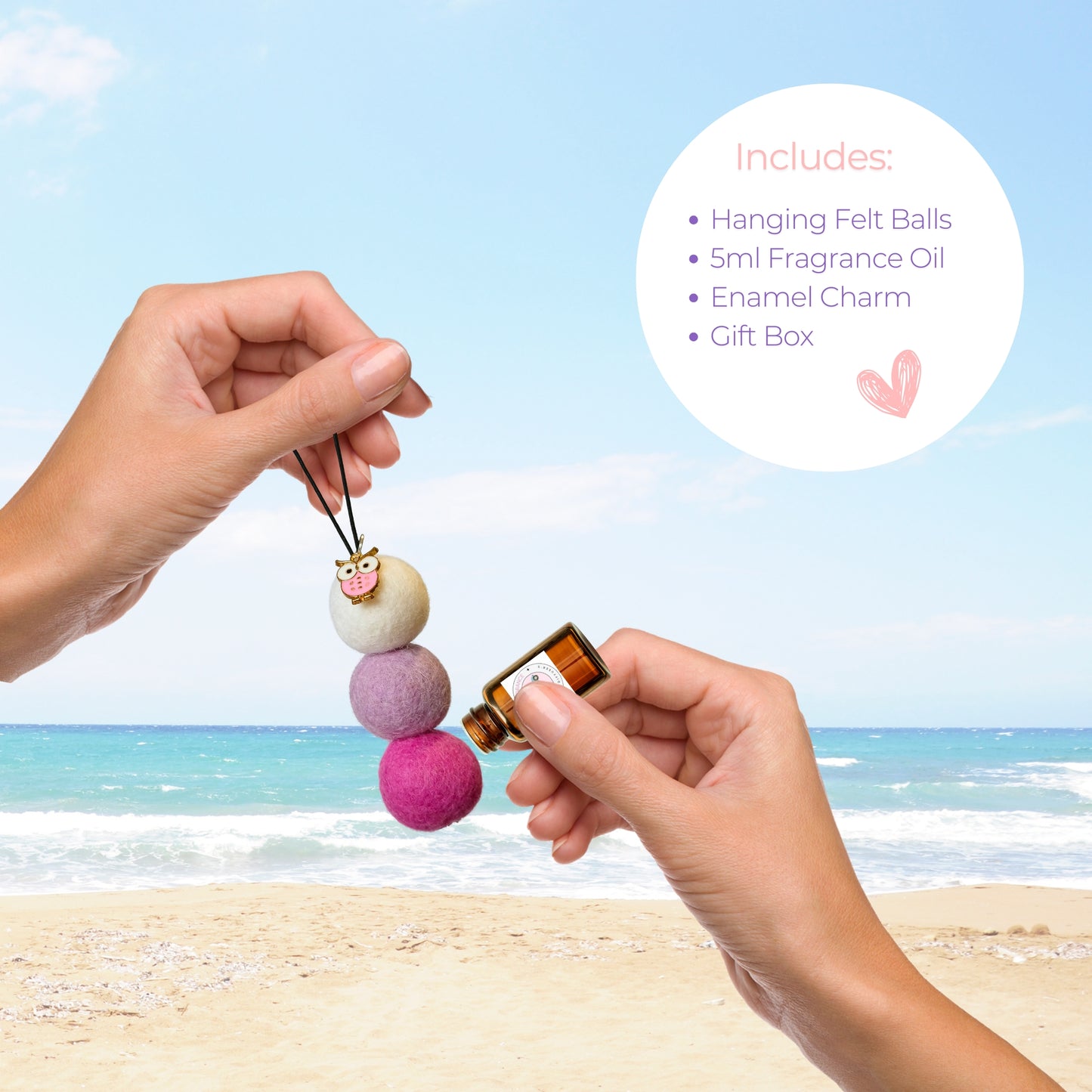 Person applying essential oil to pink owl felt ball car diffuser with product details shown at beachside.
