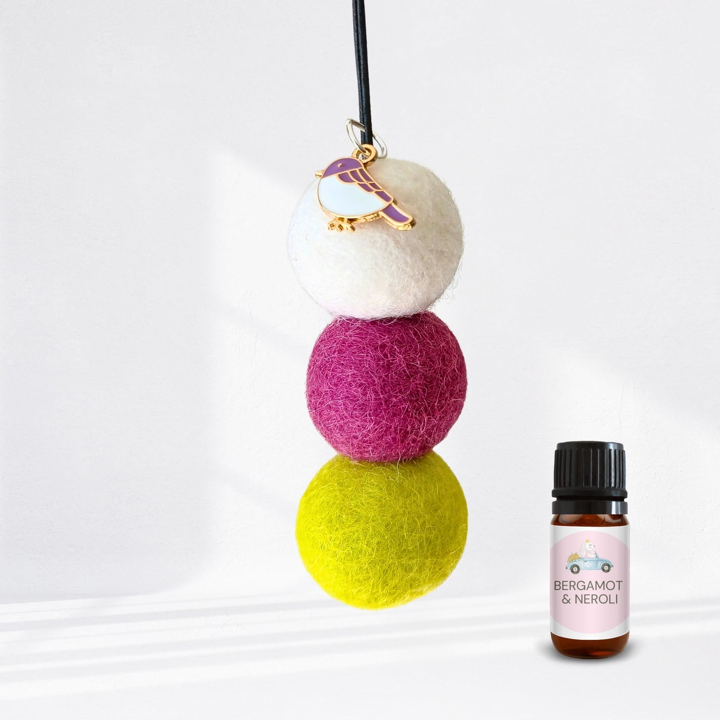Colorful felt ball diffuser with a small bottle of essential oil on a white background