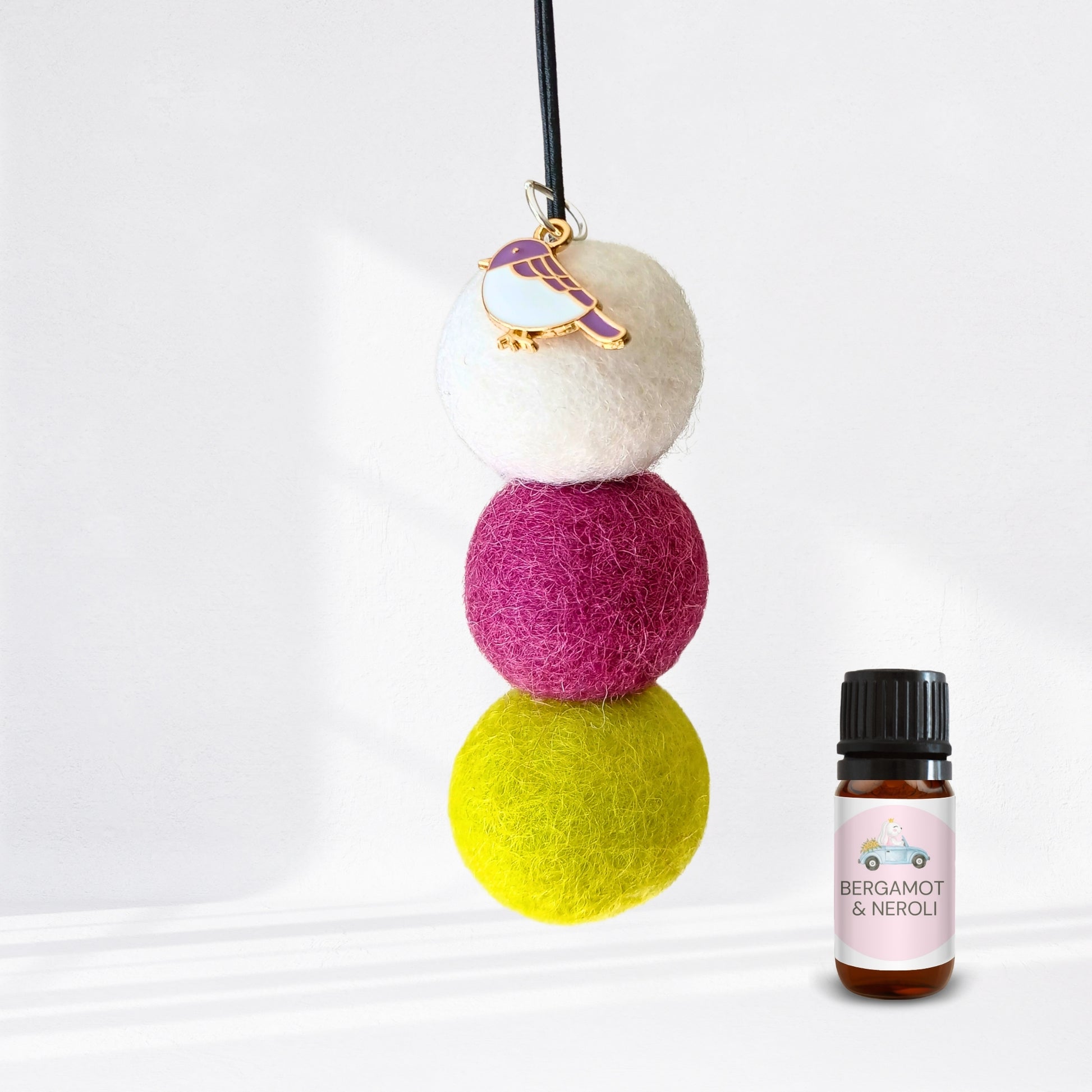 Colorful felt ball diffuser with a small bottle of essential oil on a white background