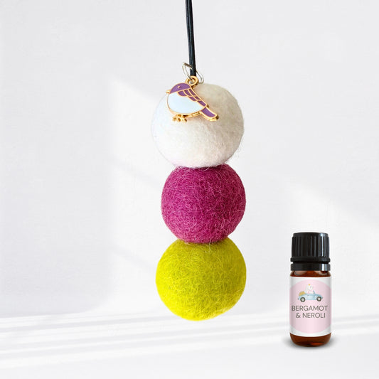 Colorful felt ball diffuser with a small bottle of essential oil on a white background