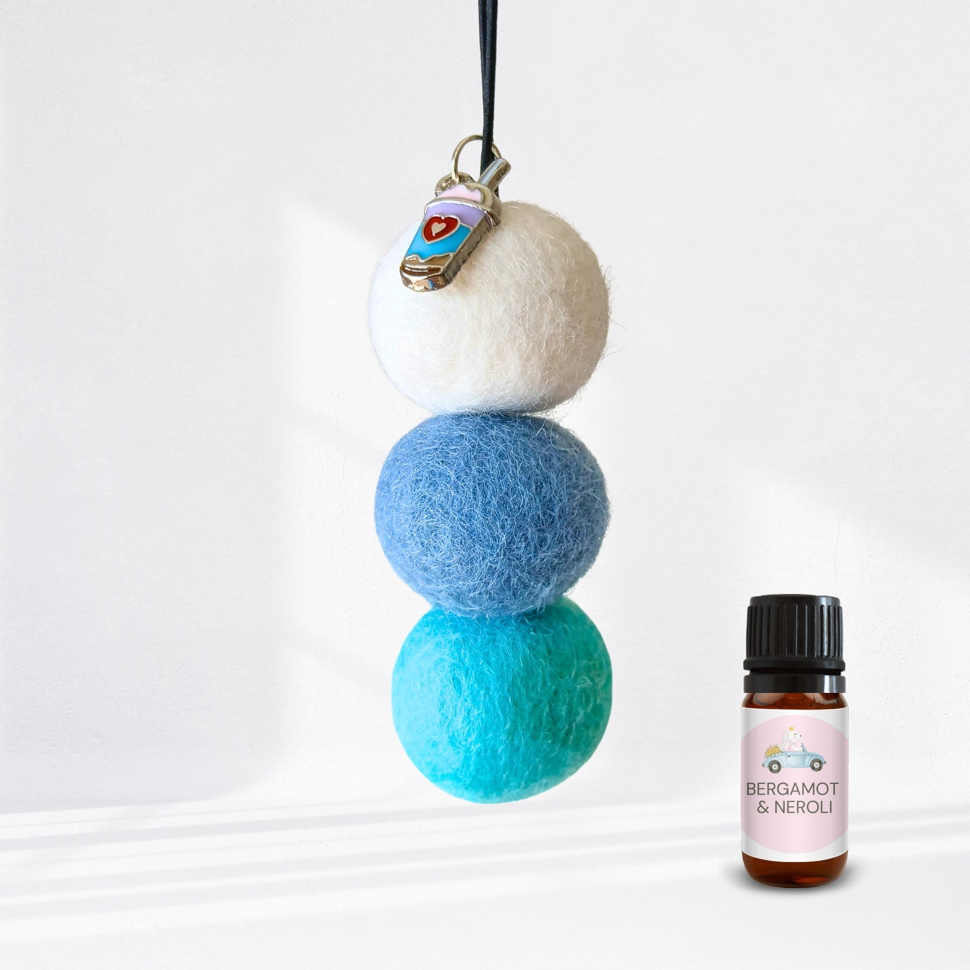 Stack of three felted balls with a bottle labelled 'Bergamot & Neroli' on a white background