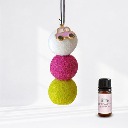 Colorful felt ball diffuser with a small bottle of essential oil on a white background