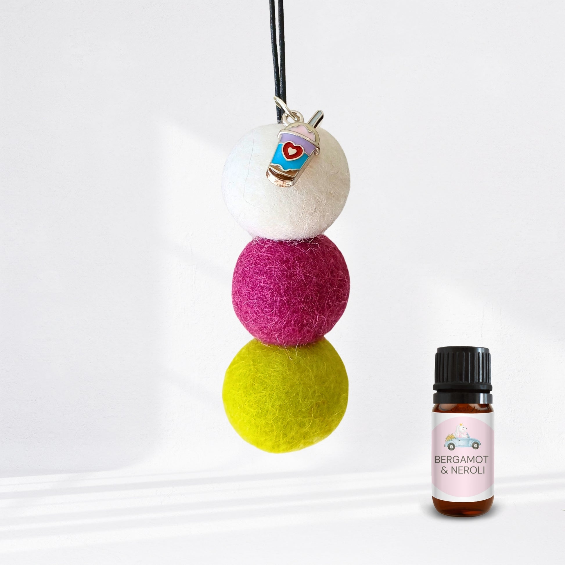 Colorful felt ball diffuser with a small bottle of essential oil on a white background