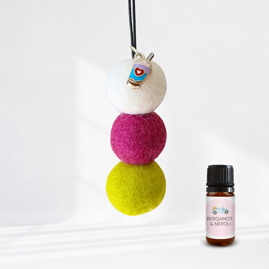 Colorful felt ball diffuser with a small bottle of essential oil on a white background