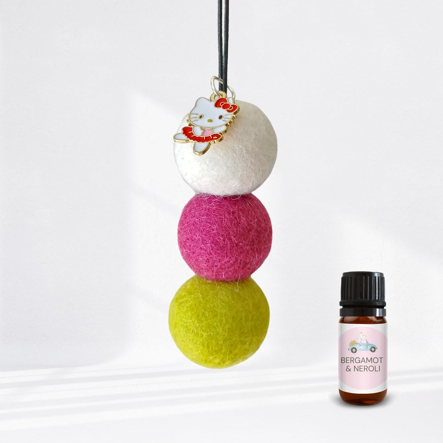 Three colorful felt balls with a small bottle labeled 'Bergamot & Neroli' on a white background