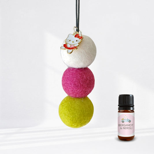 Three colorful felt balls with a small bottle labeled 'Bergamot & Neroli' on a white background