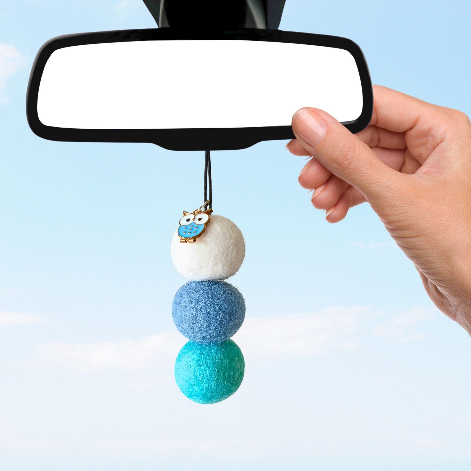 Car mirror with a decorative hanging charm featuring three colorful felt balls.