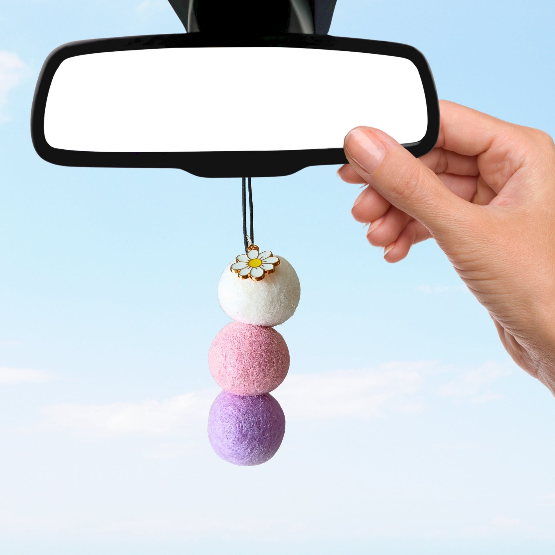 Pastel-colored car charm with a flower pendant attached to a car's rearview mirror.