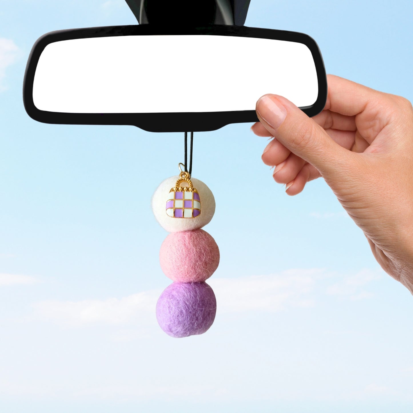 Colorful car charm hanging from a car mirror against a light blue background