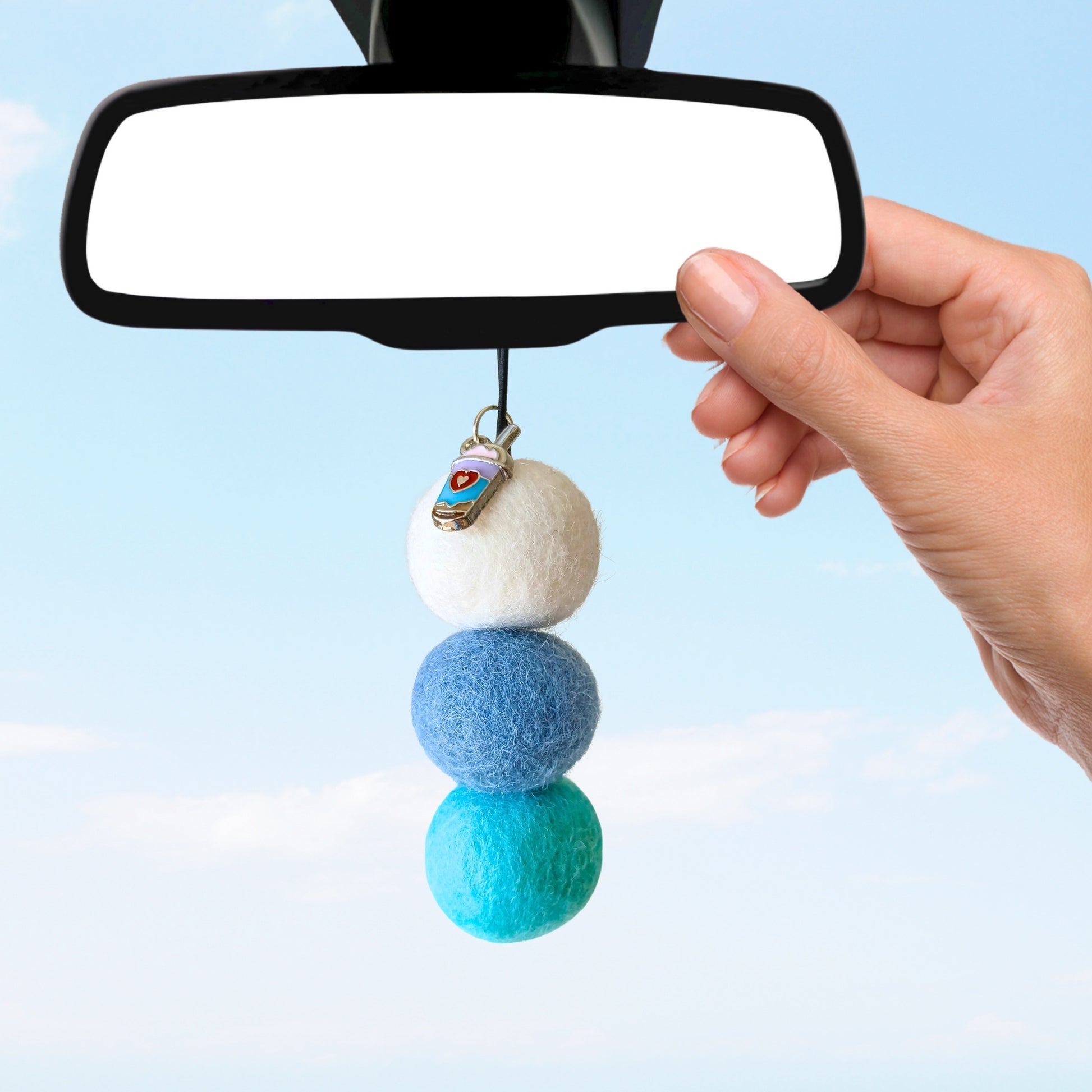 Car mirror with a decorative hanging charm featuring three colored balls.