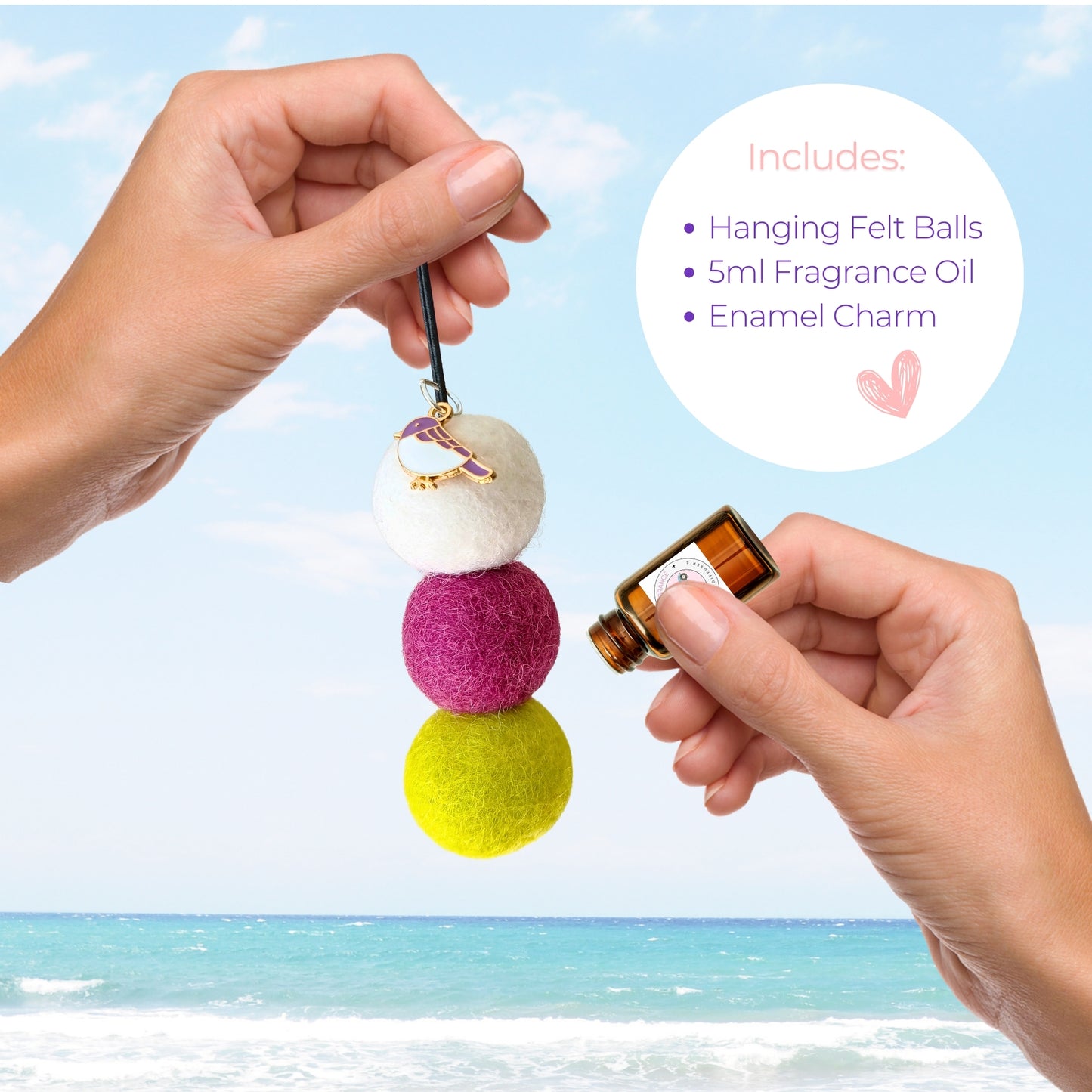 Colorful hanging felt ball diffuser with a small bottle of fragrance oil against a beach background
