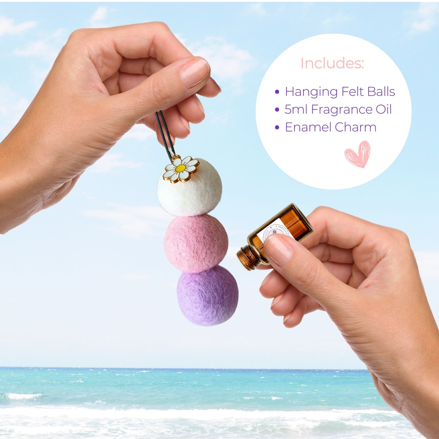 Hanging felt balls with a small bottle of fragrance oil against a beach background
