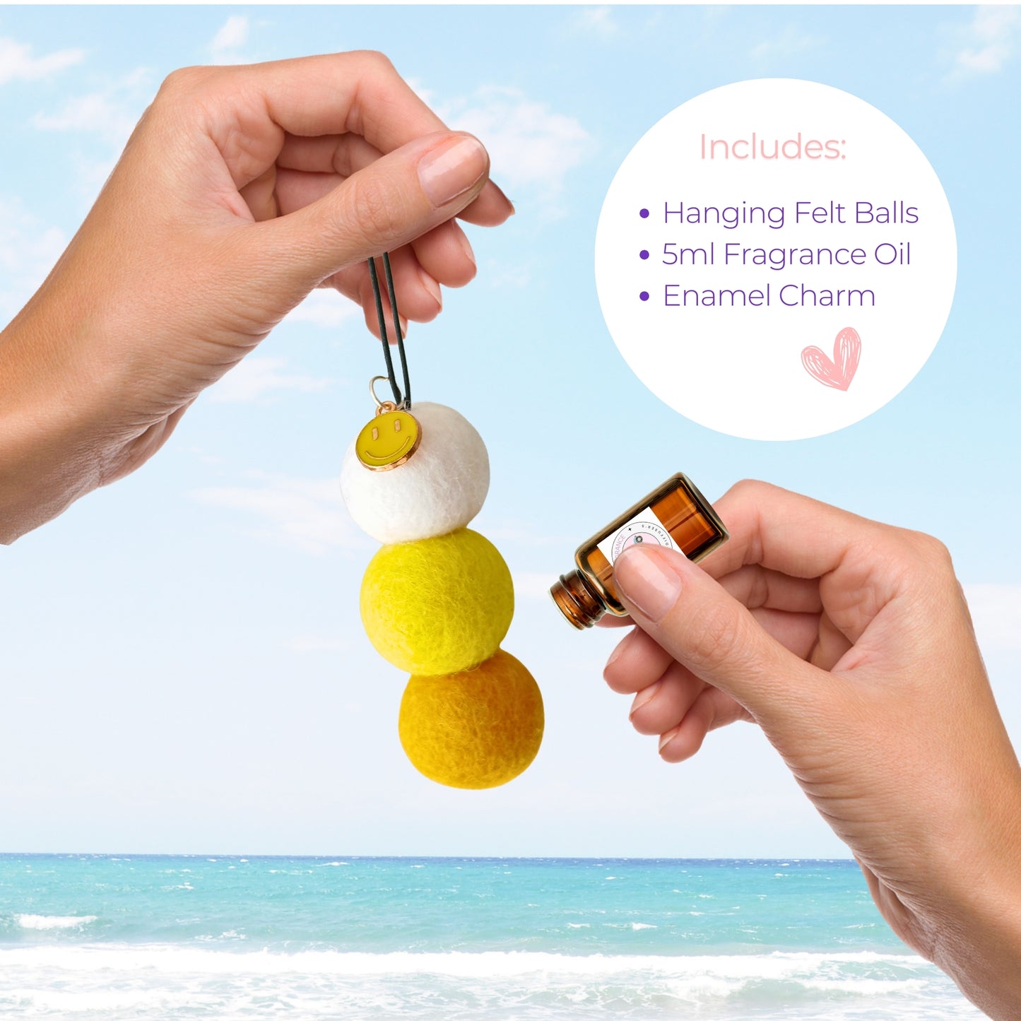 Hanging felt ball ornament with fragrance oil and enamel charm against a beach background