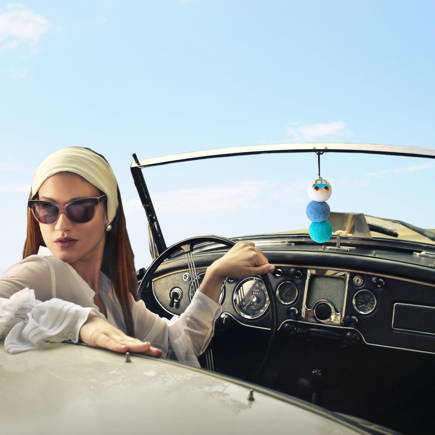 Woman sitting in a vintage car with a colorful car hanging diffuser.