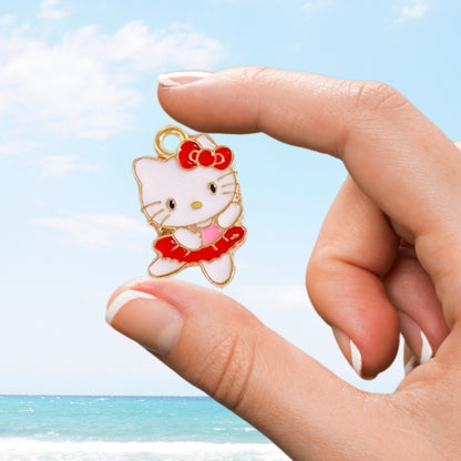 Hand holding a Hello Kitty charm against a beach background