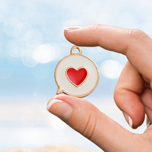 Hand holding small enamel love heart charm