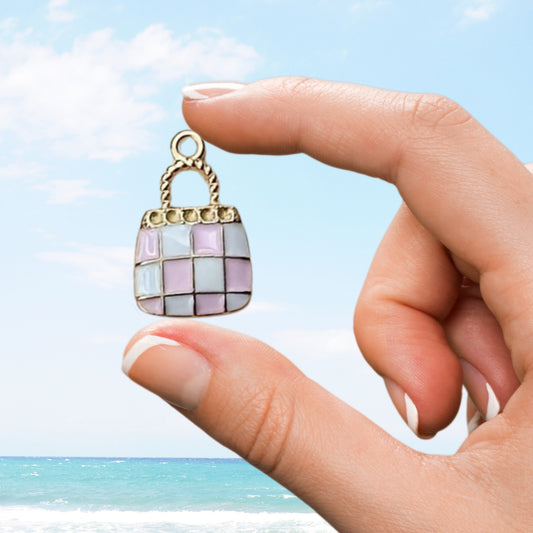 hand holding small pink enamel handbag